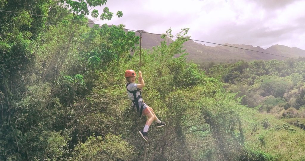 a girl on a zipline along the Big island's lush forests