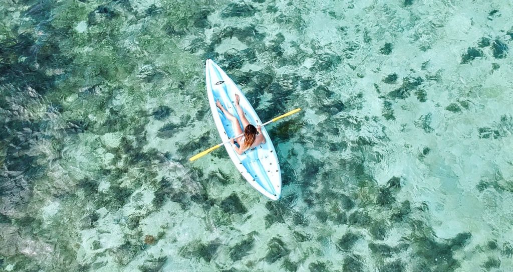 a female tourist kayaking on the turquoise waters of the Big Island of Hawaii