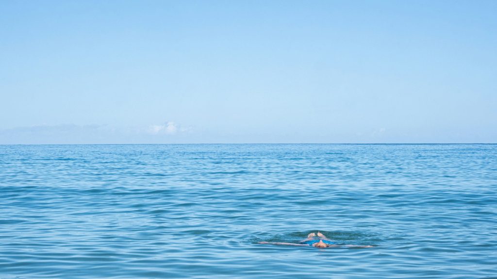 person floating on the ocean water at Mauna Kea Beach