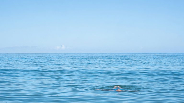 person floating on the ocean water at Mauna Kea Beach