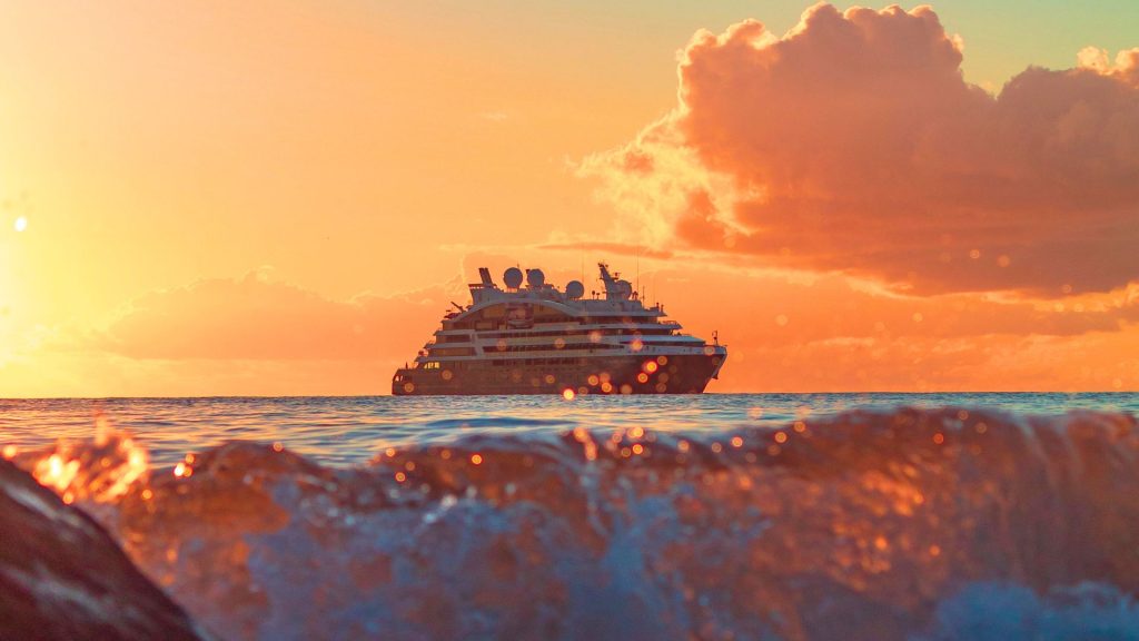 A cruise ship out at sea under the sunset skies